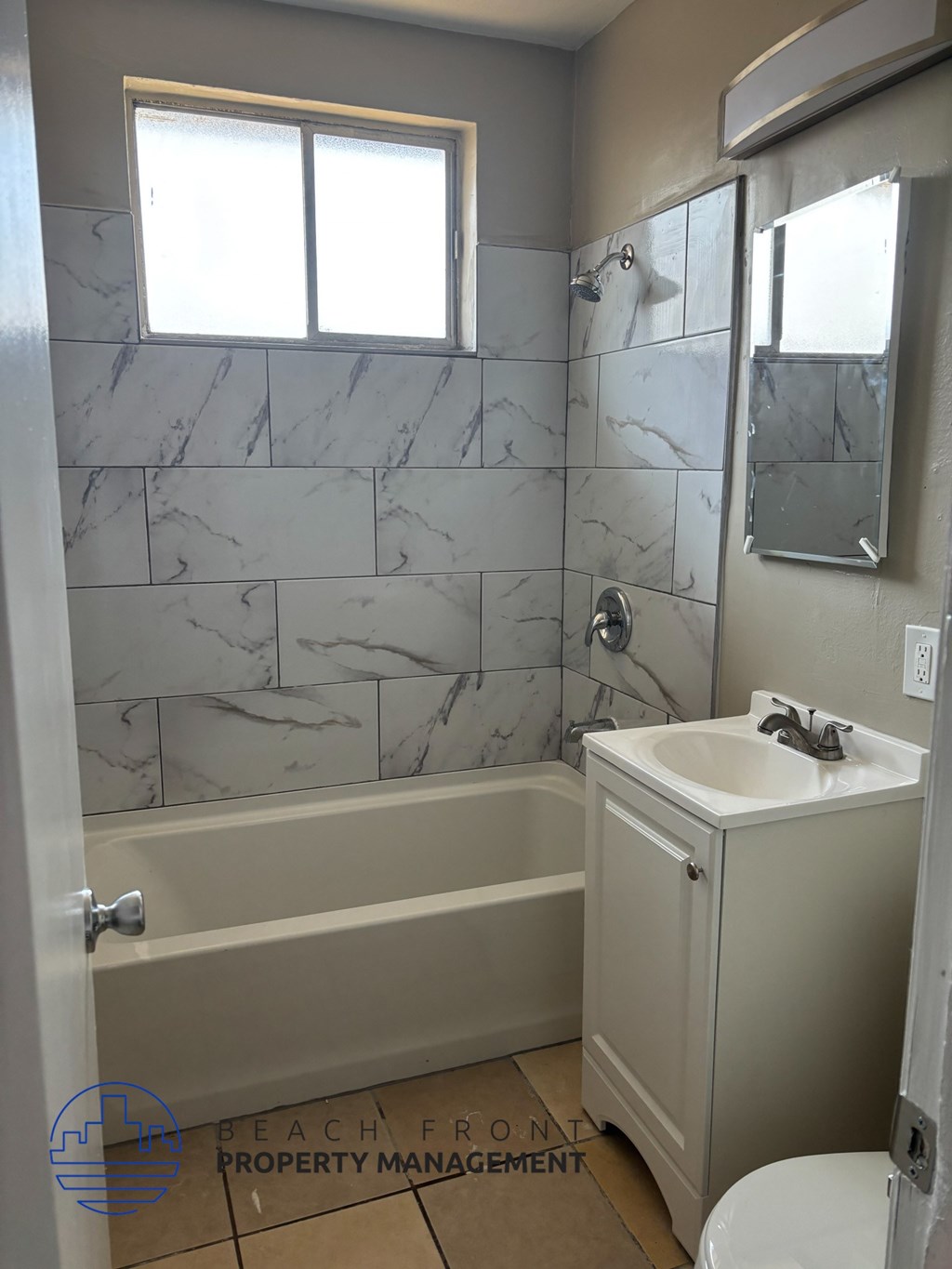 A bathroom with a marble tile wall and a white sink.